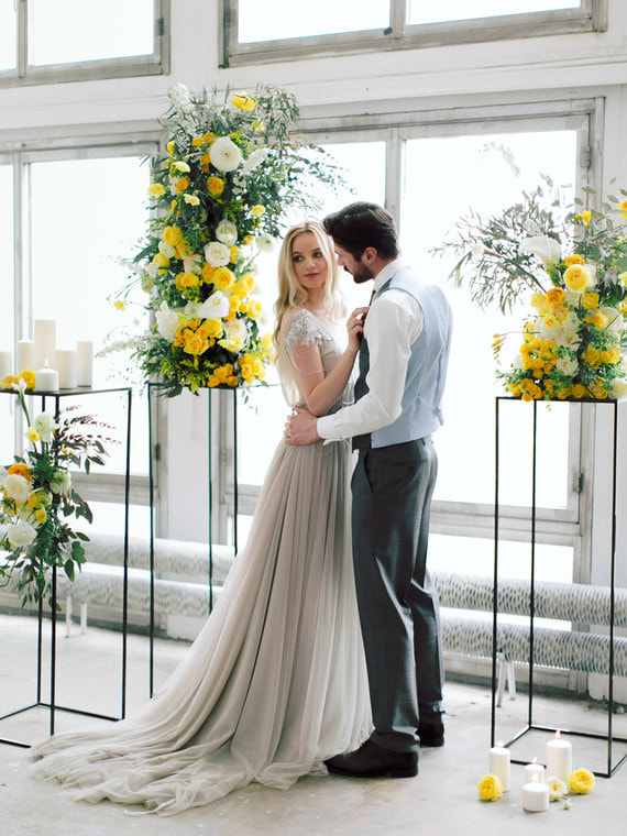 Gray chiffon bridal gown stands out against yellow floral decor in this muted venue.