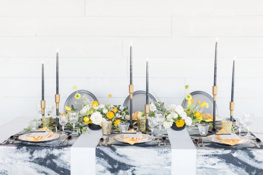 A gray marbled table top featuring gray accent decor softened with yellow florals.