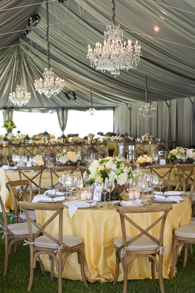 Grey chiffon tent liner with chandeliers and yellow table cloths.